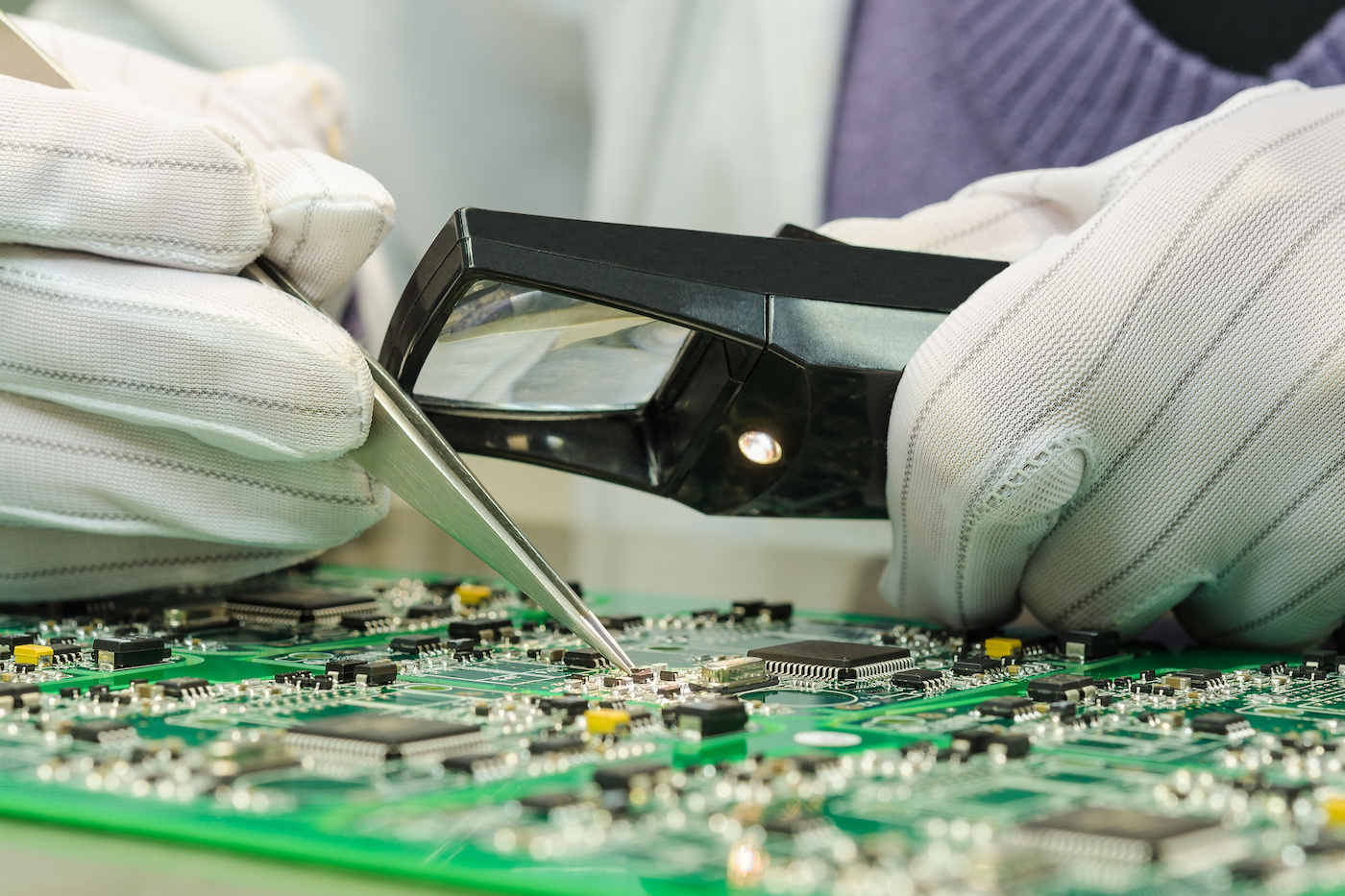 Woman in antistatic gloves holding pincette and magnifier